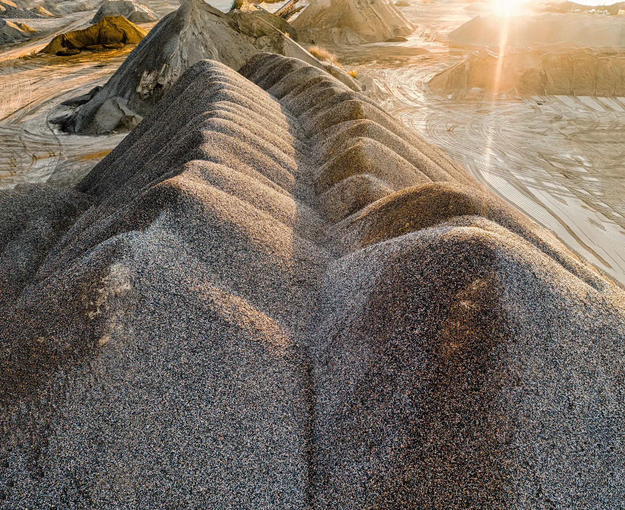 A long ridged gravel stockpile in low evening sun at a quarry